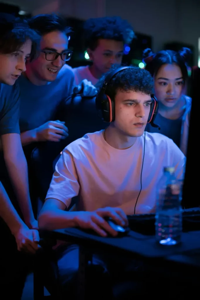 Gamer playing with headphones on, but surrounded by people.